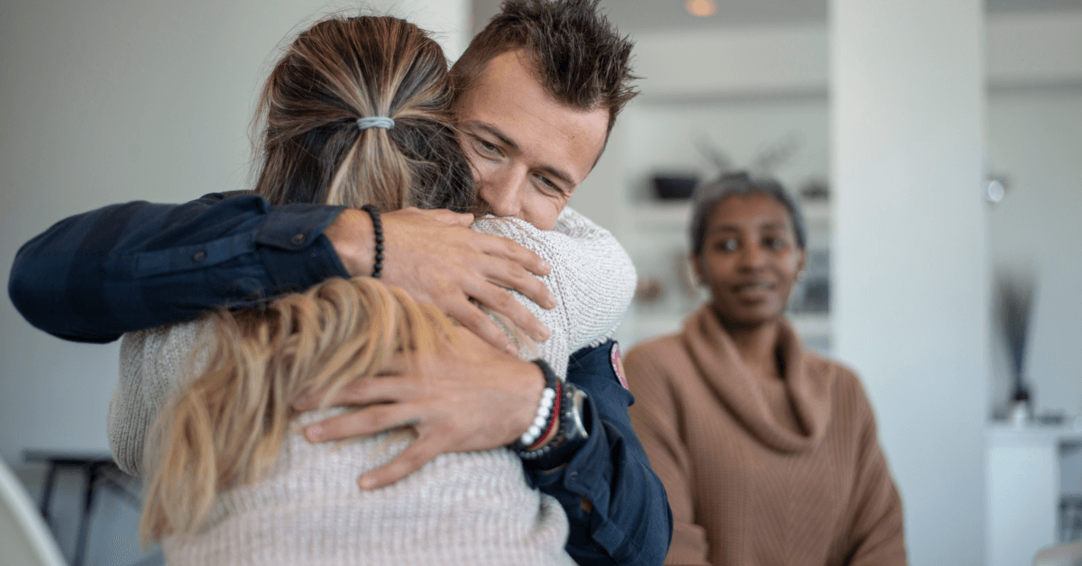 A man is comforting a woman in an office as she strives to overcome addiction