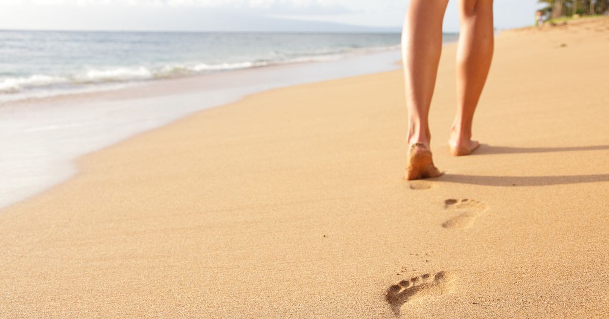 A woman finding solace walking on a beach, seeking to overcome addiction.