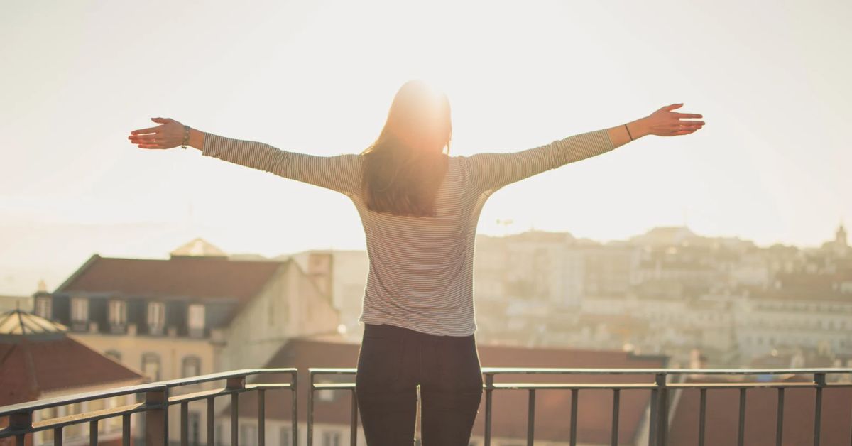 A woman on a balcony overlooking a city, embracing recovery from addiction.
