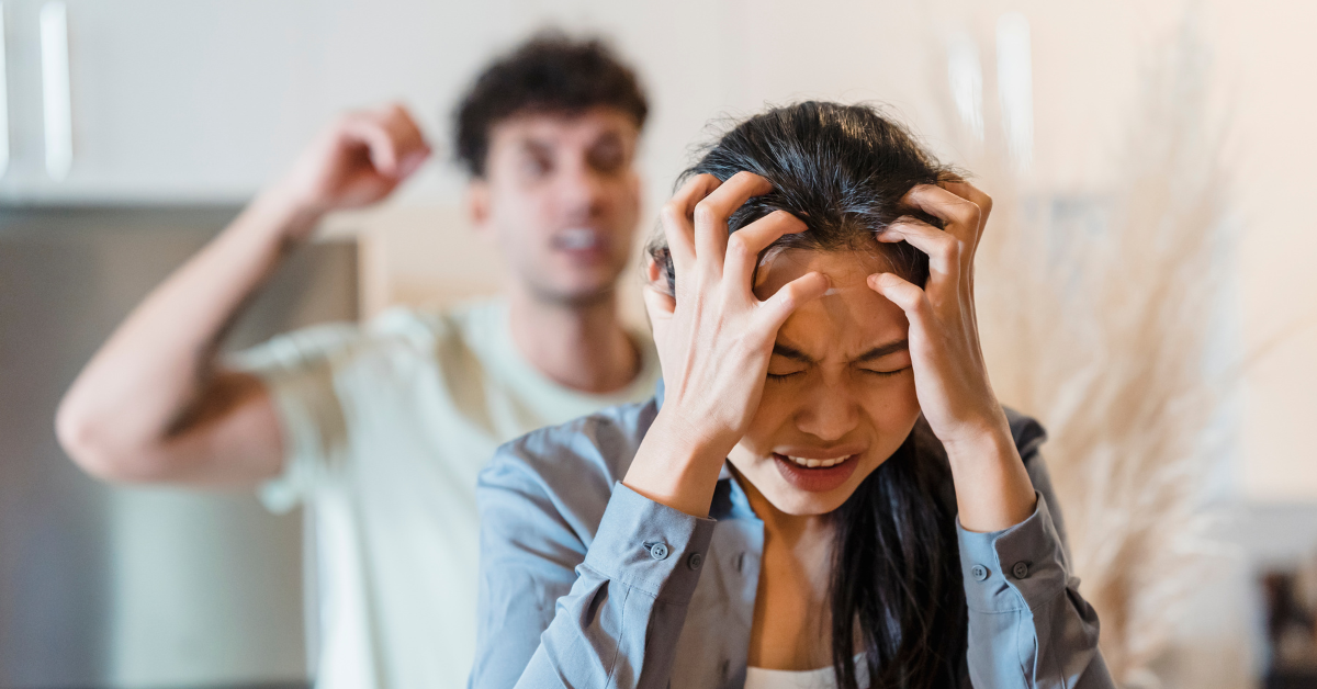 A woman is holding her head in front of a man because of chaos.