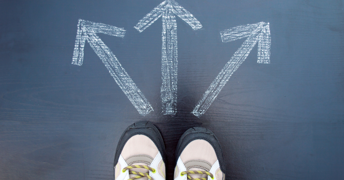 A person using decision making skills in recovery stands on a blackboard with arrows drawn on it.