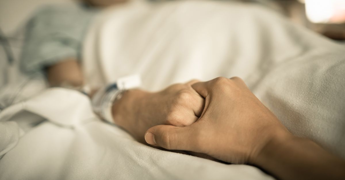 The hand of a patient in a hospital bed showing symptoms of a heroin overdose.