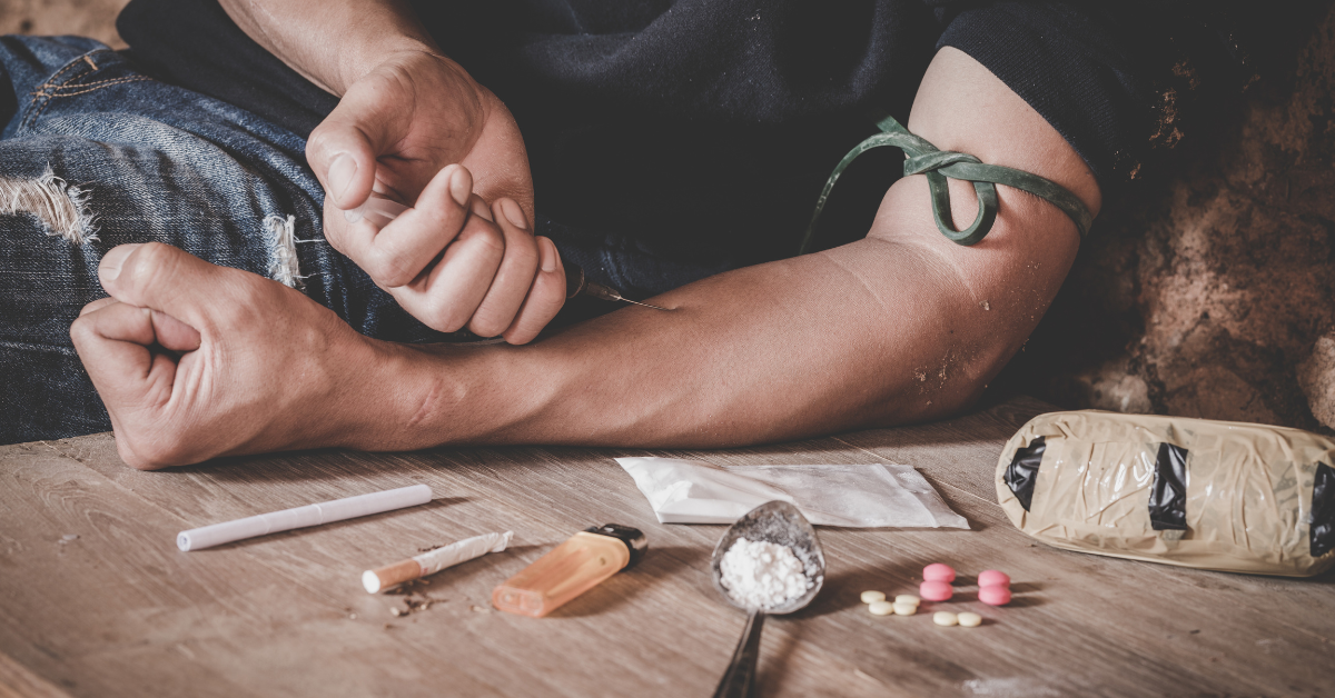 A teenager struggling with heroin addiction surrounded by drugs and a syringe on a table.