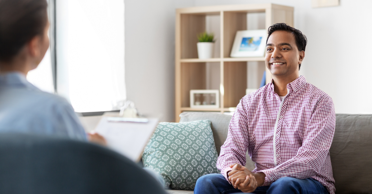 A man seeking accountability in recovery converses with a therapist while sitting on a couch.