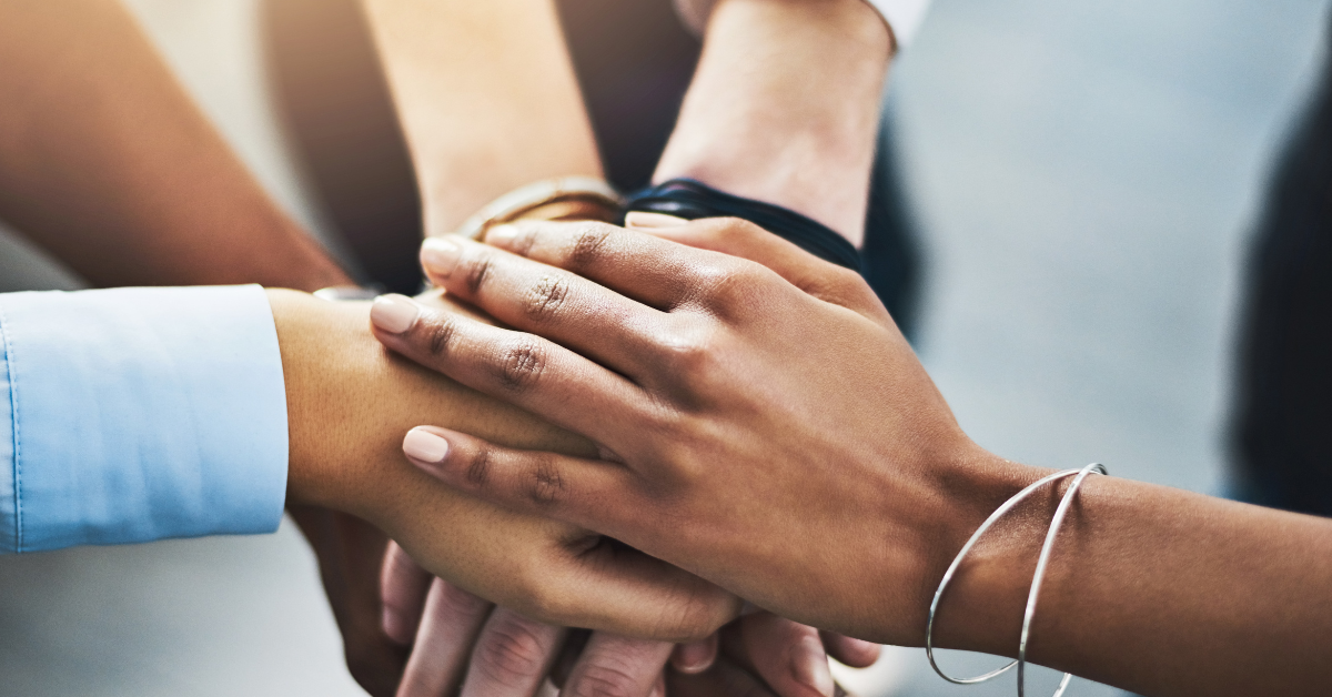 A group of people showing their commitment in recovery by putting their hands together.