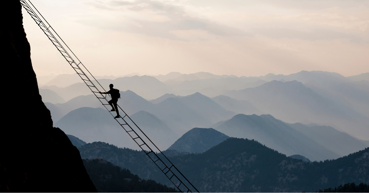 A man demonstrating courage as he climbs a ladder on a mountain in his recovery journey.