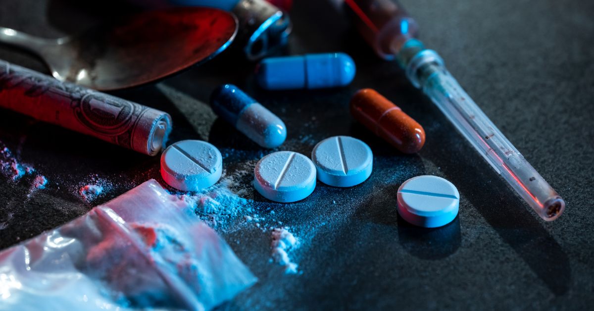 A table displaying drugs, pills, and a spoon — all symbolizing different stages of the addiction cycle.