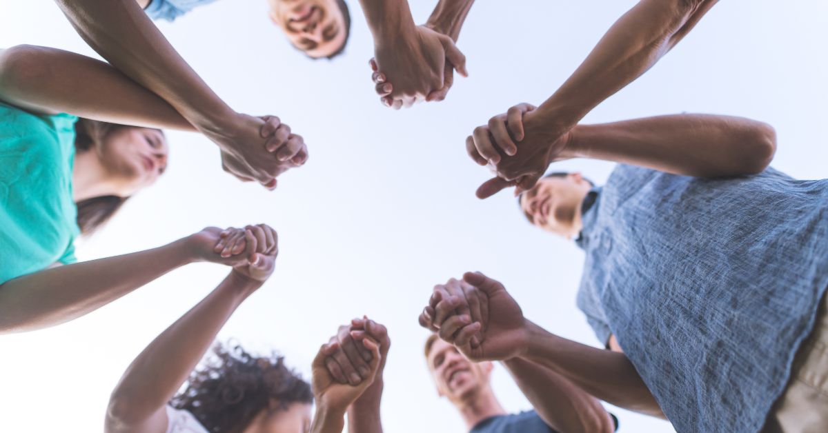 A group of people taking the last steps towards recovery, holding hands in a circle.