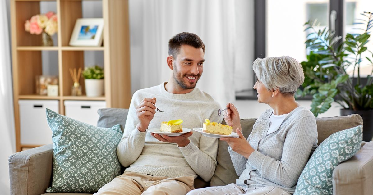 A man and his mother finding motivation for recovery while eating cake on a couch.