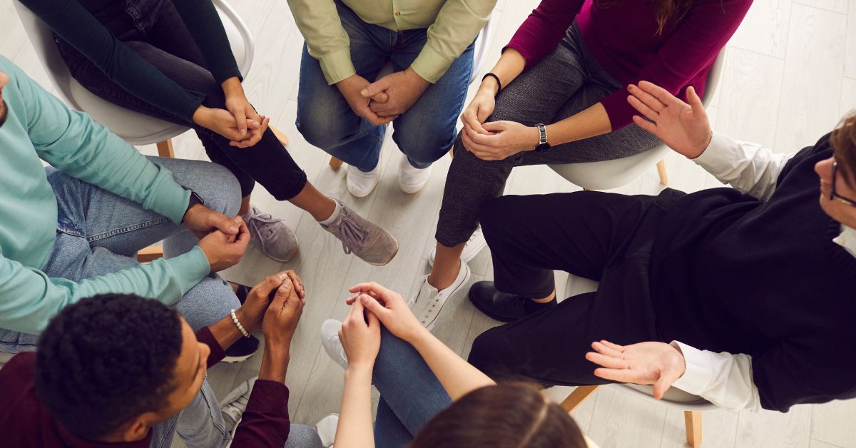 A support group staying sober in addiction recovery, sitting in a circle.