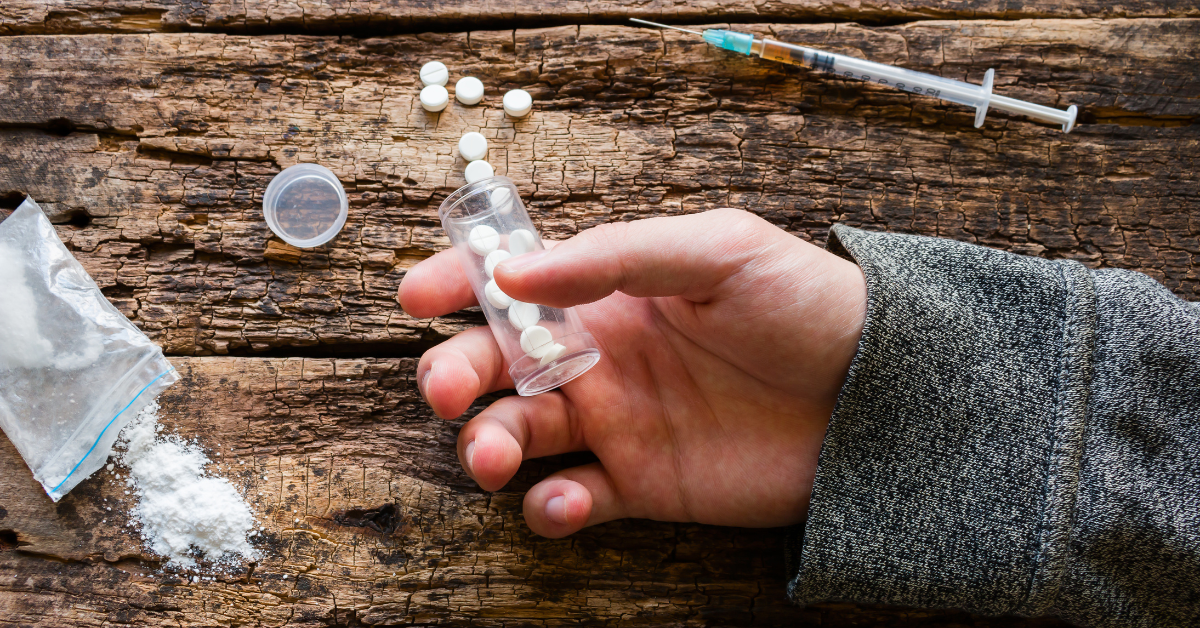 A hand holding a syringe of drugs during an IOP relapse.