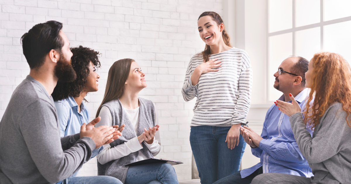 A woman talking about her early recovery from addiction with a group in a room.