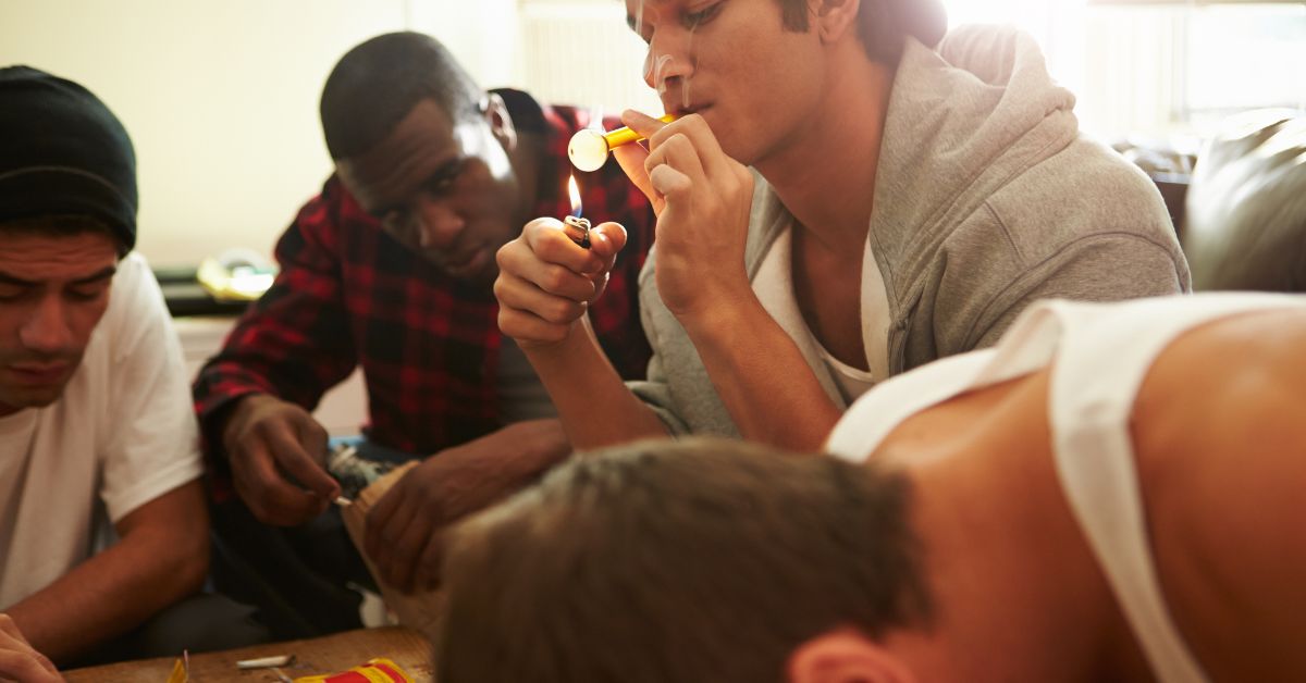 A group of young men sitting around a table playing a game while using common drugs of abuse in teens.