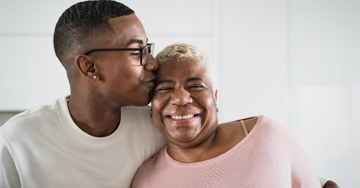 A man and his mother looking forward, fostering positive change as they embrace in the kitchen.