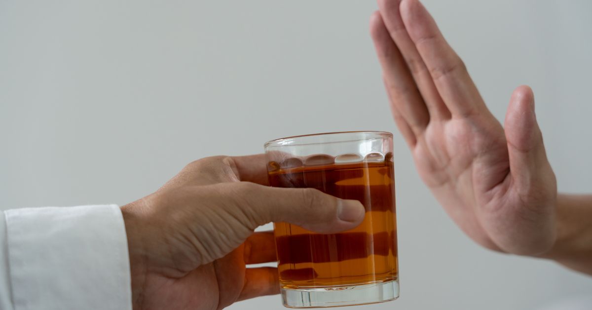 A parent setting a good example by handing a glass of alcohol to another person.