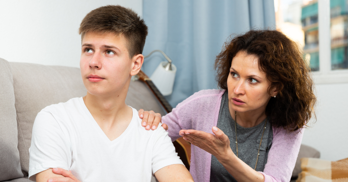 A woman is talking to her drug addict son on the couch, filled with concern.
