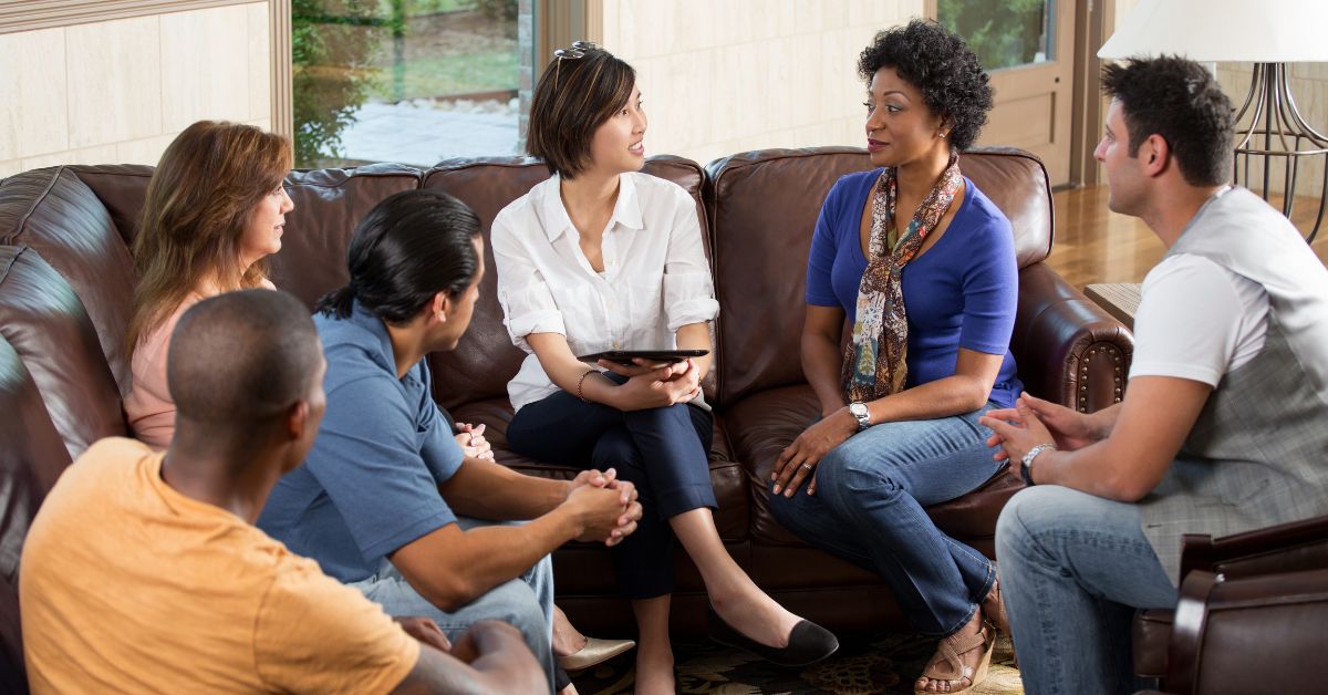 A group of people who loves someone in addiction supporting and practicing coping mechanisms around a couch.