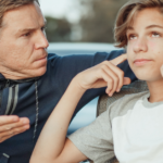A father is engaging in a conversation with a boy sitting on a bench, discussing why adolescence is a crucial time to prevent drug abuse.