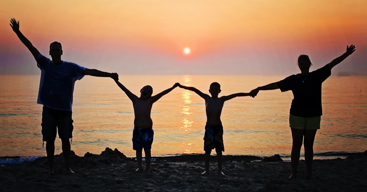 Silhouettes of a family rebuilding relationships on the beach at sunset.