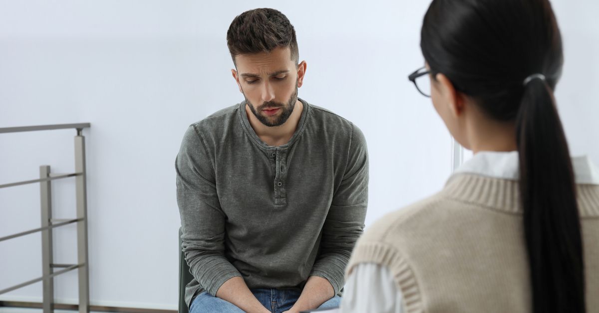 A man experiencing crack withdrawal symptoms talks to a woman in an office. 