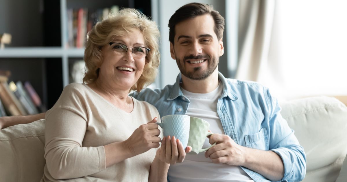 A mother and her son calmly sitting on a couch holding a cup of coffee while coping with high risk situations for recovery.