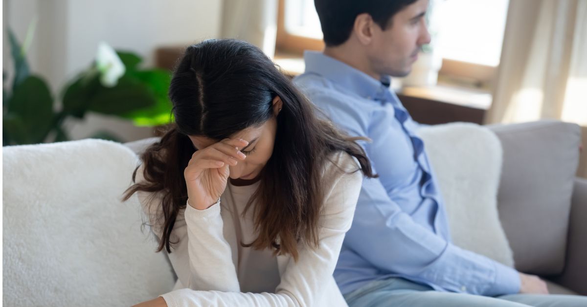 A couple sitting on a couch in a living room dealing with manipulative action and denial during addiction.