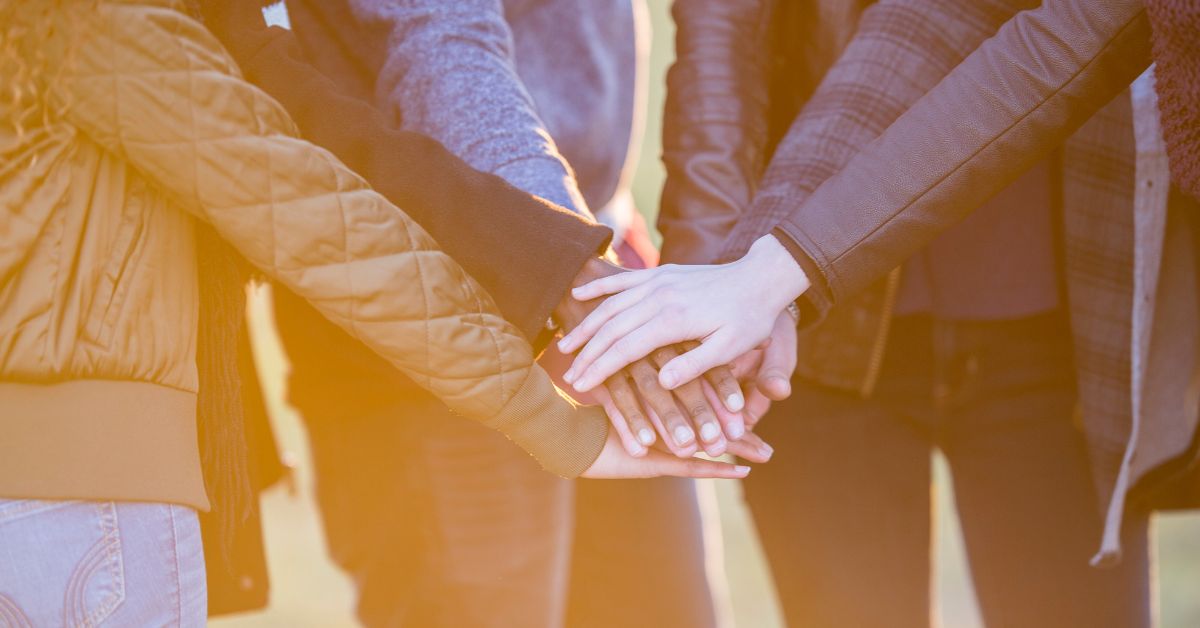 A group of people holding hands in a circle, making new friends in recovery.