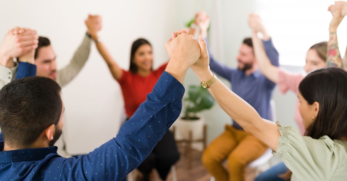 A circle of people raising their hands, demonstrating decision making in recovery.