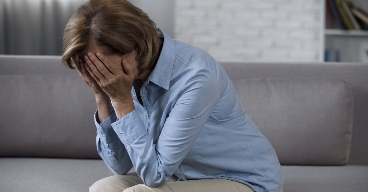 A woman sitting on a couch trying to overcome denial of her addiction.