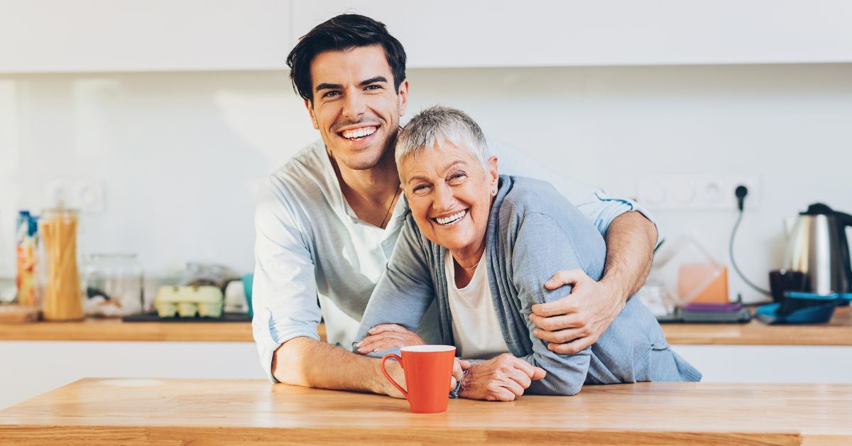 A man and his mom embracing in the kitchen, overcoming self-sabotaging behavior for a better life.