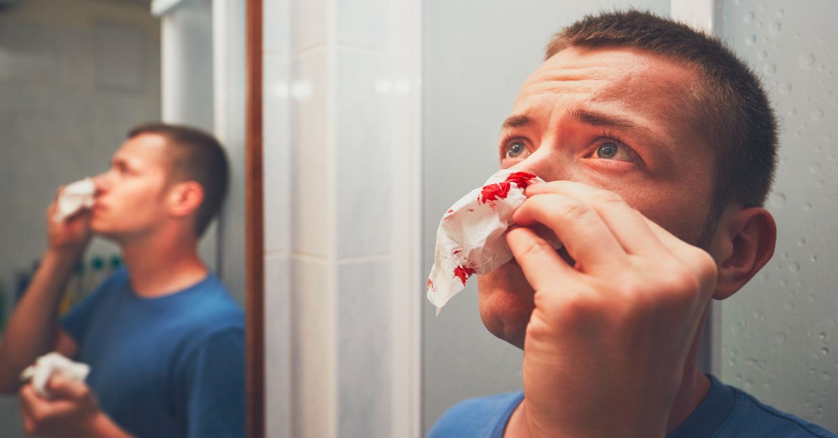 A man recognizing signs of cocaine abuse in front of a mirror.