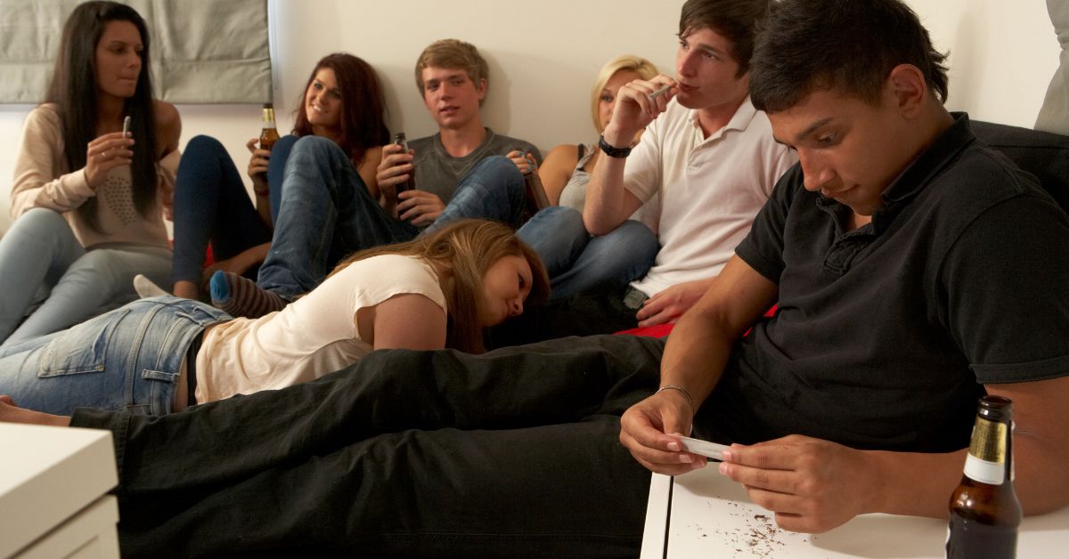 A group of teenagers using marihuana on a couch exemplifies potential risk factors for teen drug abuse.