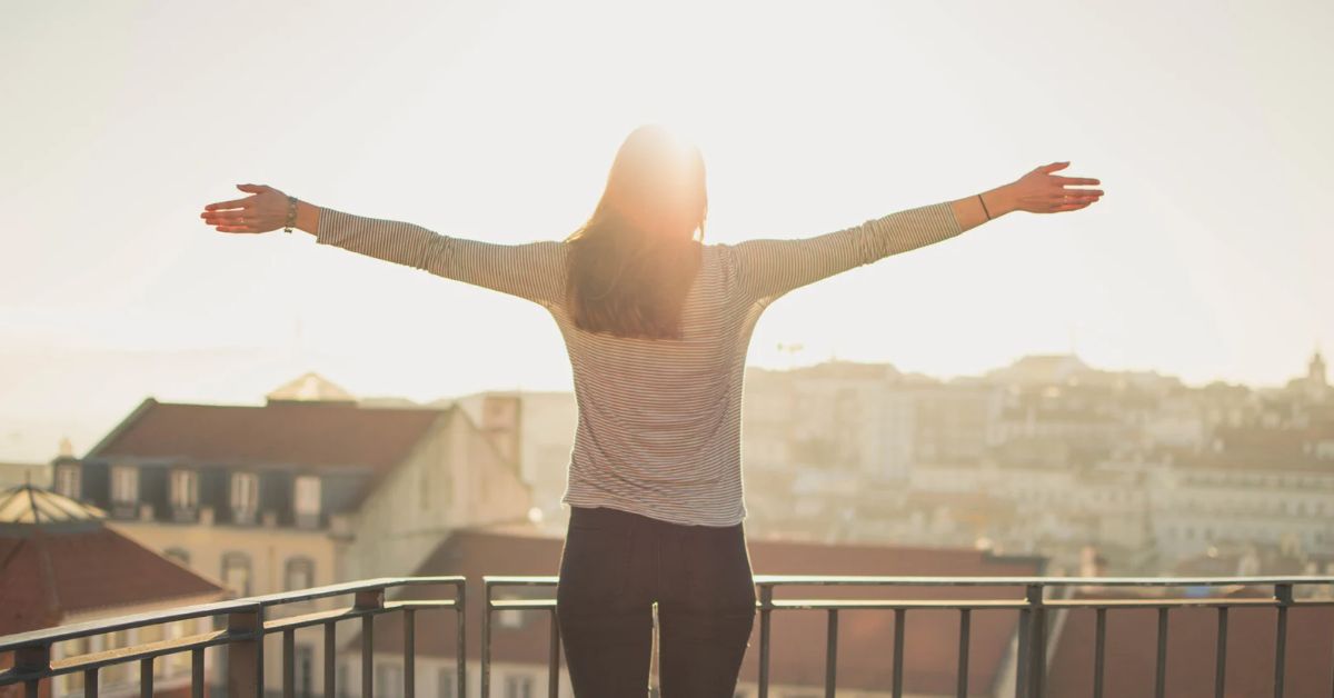 A woman on a balcony overlooking a city, embracing recovery from addiction. 