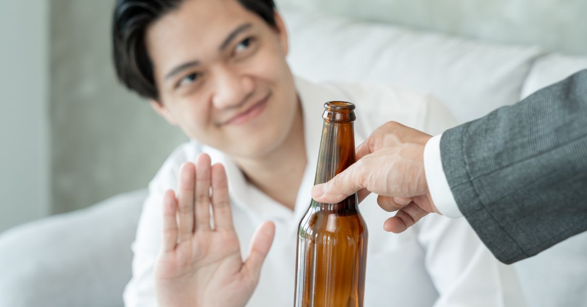 A teenager is rejecting a drink offered by another man.