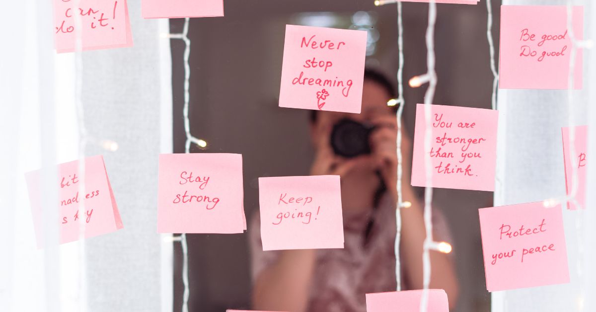 A woman using strategies to develop courage is seen taking a picture of pink post it notes on a window.