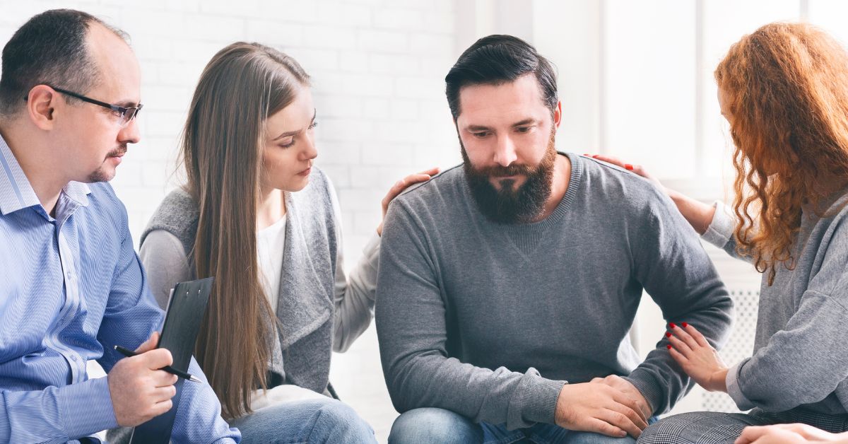 A group of emotionally unavailable people sitting on the floor and discussing why alcoholics cannot love each other.