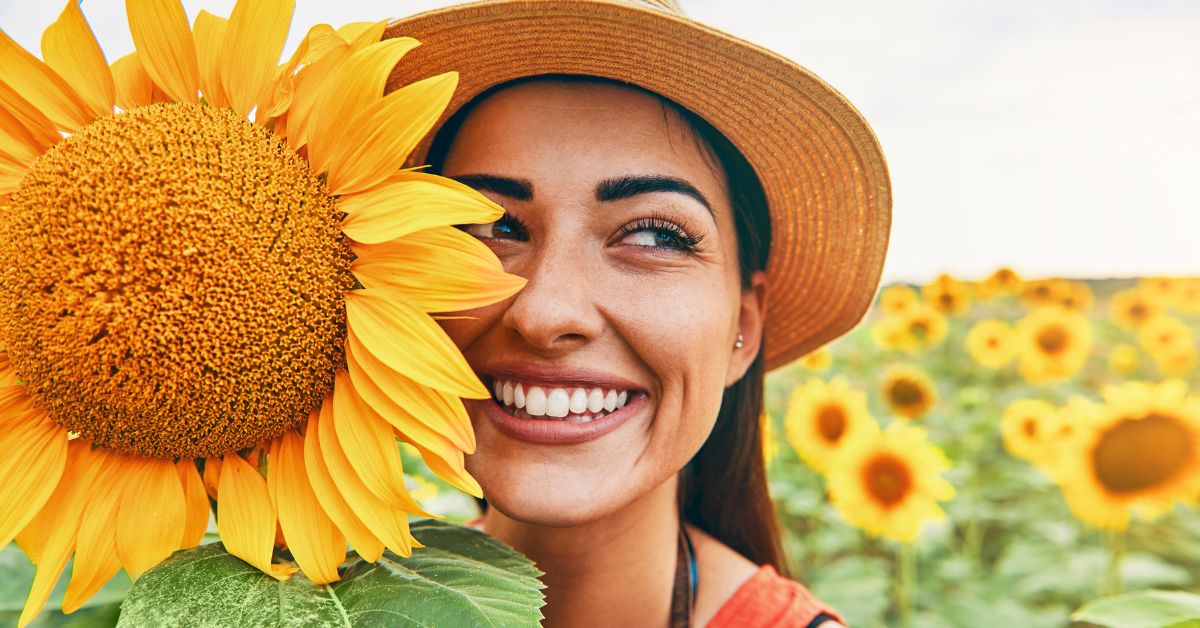 A woman is confidently holding a sunflower in front of her face, highlighting the importance of self confidence in addiction treatment.