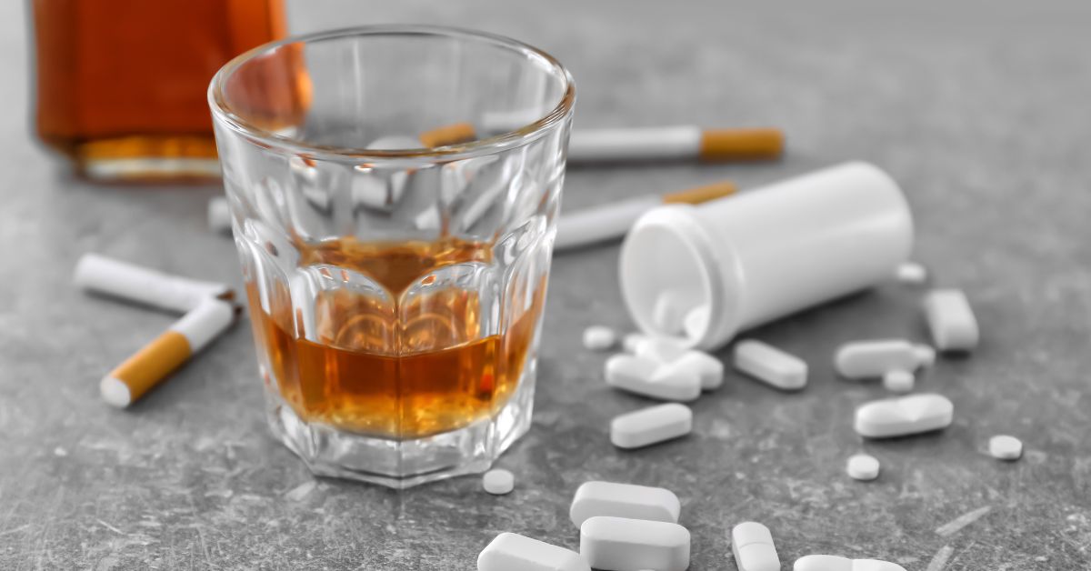 A glass of alcohol and pills on a table depicting teen drug use.