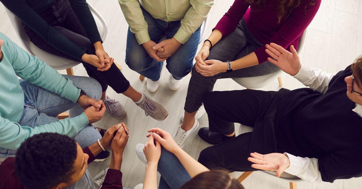 A group of people sitting in a circle discussing how to help an addict in denial.