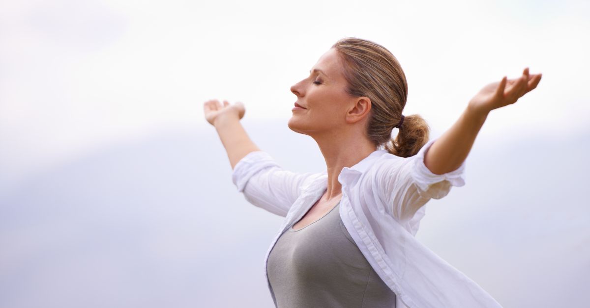 A woman with her arms outstretched in the air after discovering how to stop being addicted to chaos