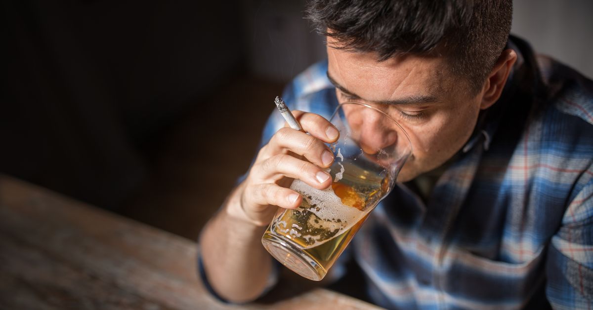 A man blaming others while drinking whiskey and smoking.