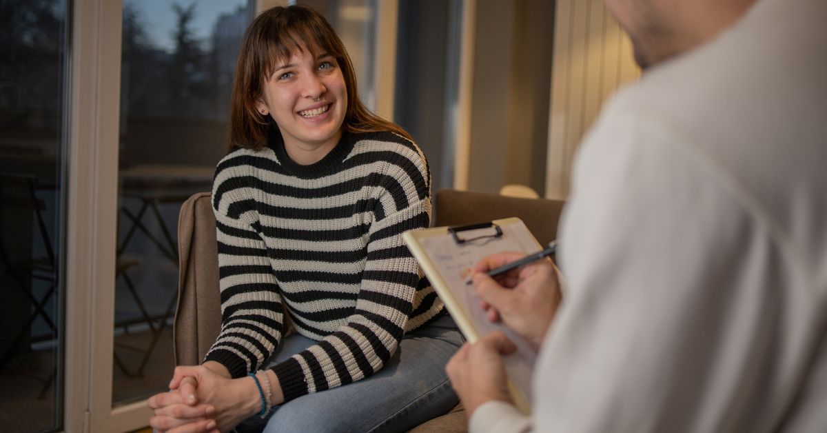 A woman sitting on a couch, engaging in an unveiling conversation with a therapist regarding her recovery journey from addiction.